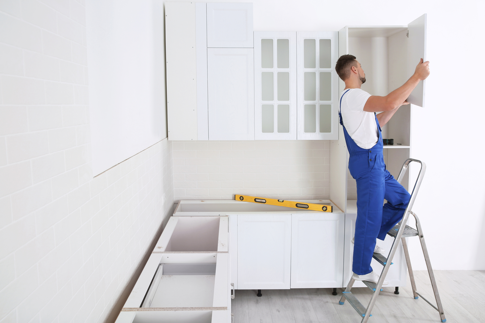 Worker installing door of cabinet in kitchen